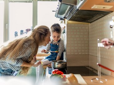 Frau kocht mit Kind in der Küche 