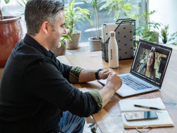Mann sitzt am Schreibtisch vor dem Notebook in einer Videoberatung