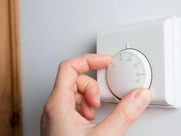 eine hand dreht ein thermostat