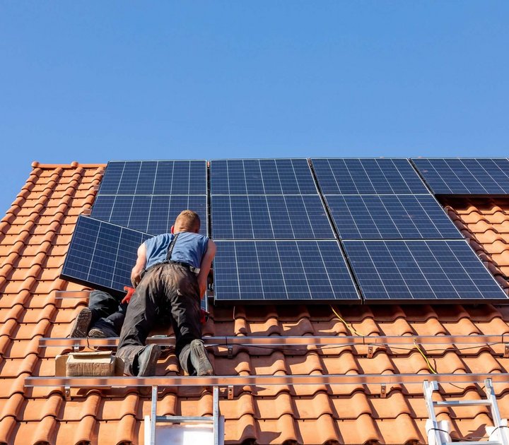 ein mann bringt eine solaranlage auf einem dach an